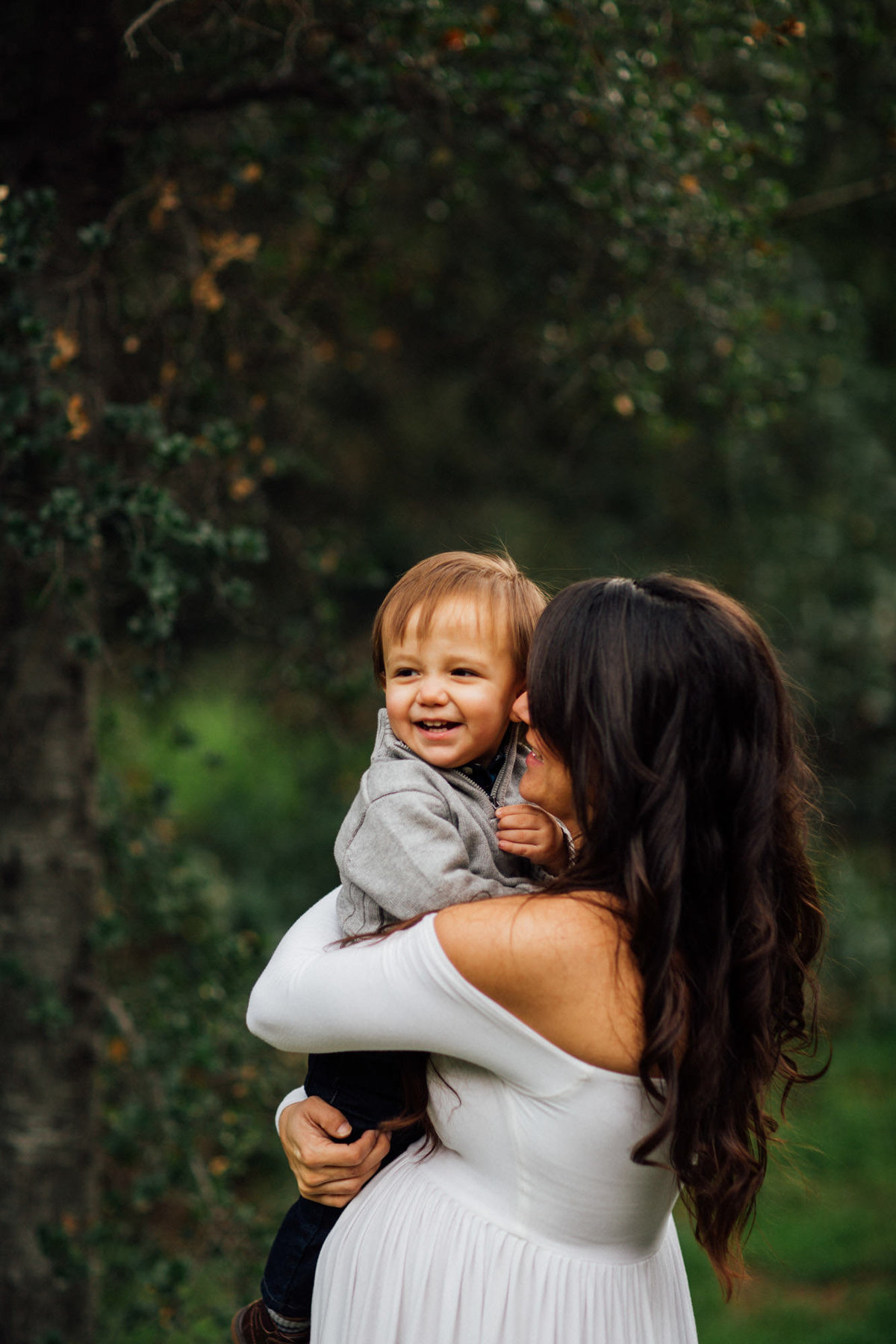 Pregnant mom lifts up her other child during a maternity session