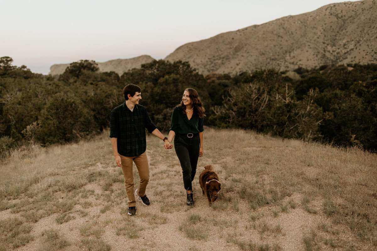 engaged couple walking with their dog at the Sandia Mountain foothills in Albuquerque