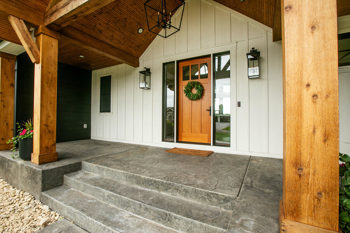 Exterior view of custom home in Otsego, Minnesota with modern wood details and front porch built by Cornerstone Custom Builds