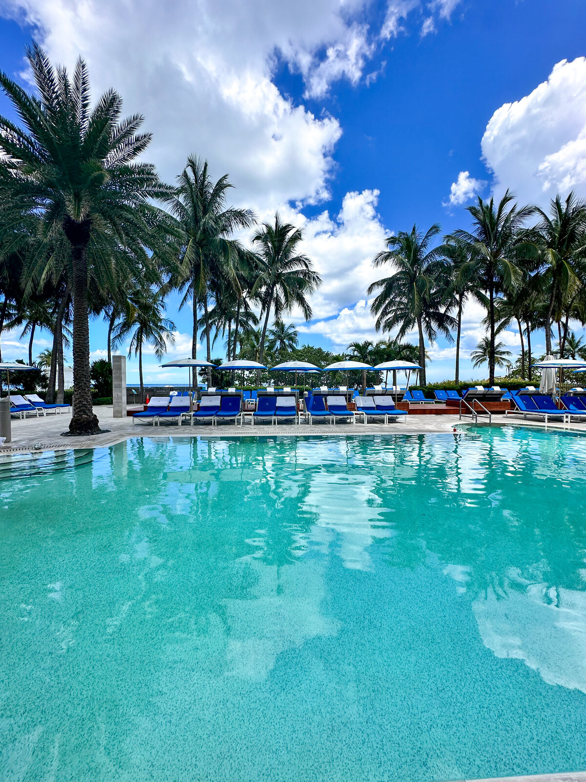  Luxurious beachfront pool surrounded by palm trees and blue cabanas at the St. Regis Bal Harbour, steps from PH-888