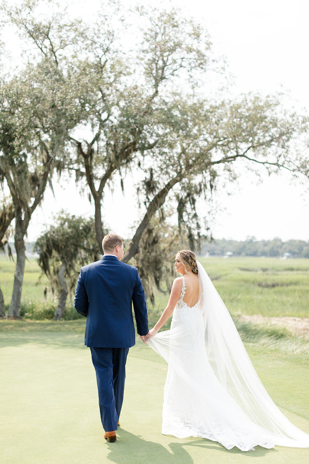 Bride and groom walking on golf course at Long Cove Club; Hilton Head Island, South Carolina