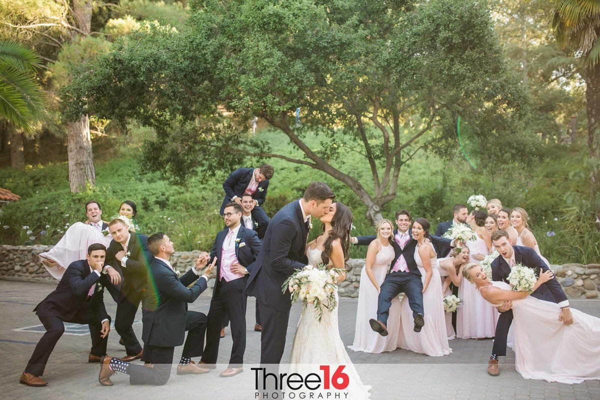 Bridal Party goofs off as Bride and Groom share a kiss