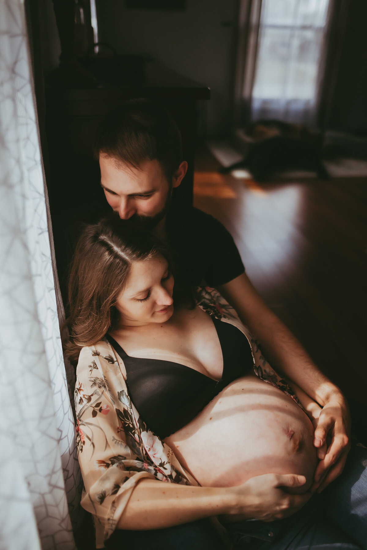 pregnant couple snuggles and holds belly
