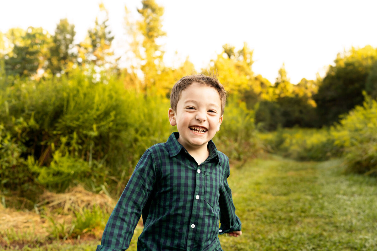 Young boy laughing and running through field