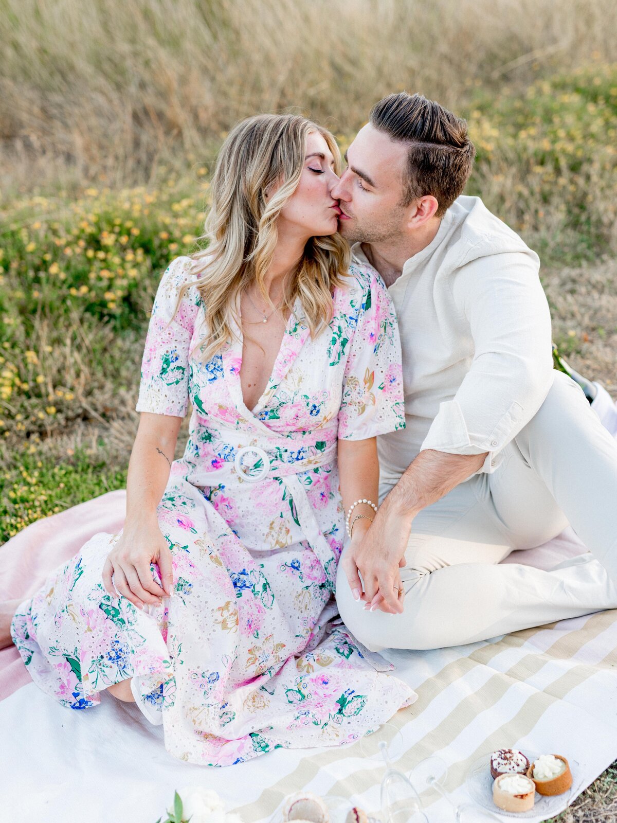 Romantic kiss during a golden hour picnic engagement in San Luis Obispo—soft florals, sweet connection, and California charm.
