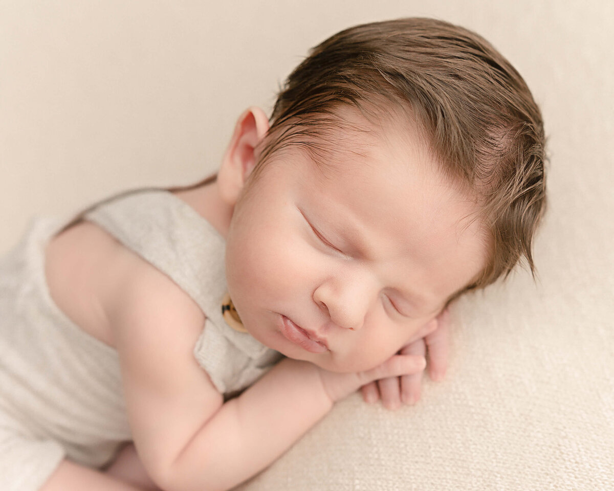baby boy with head on hands sleeping in studio photography session