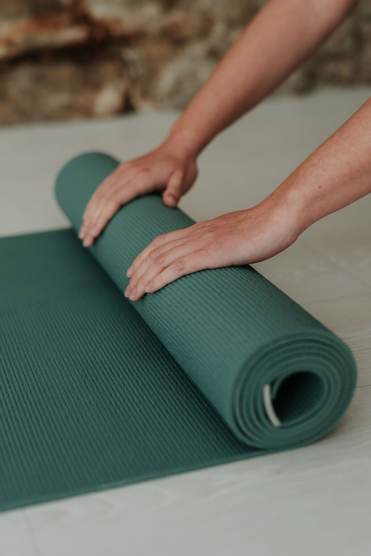 Close up of pilates instructor rolling up sage green pilates mat