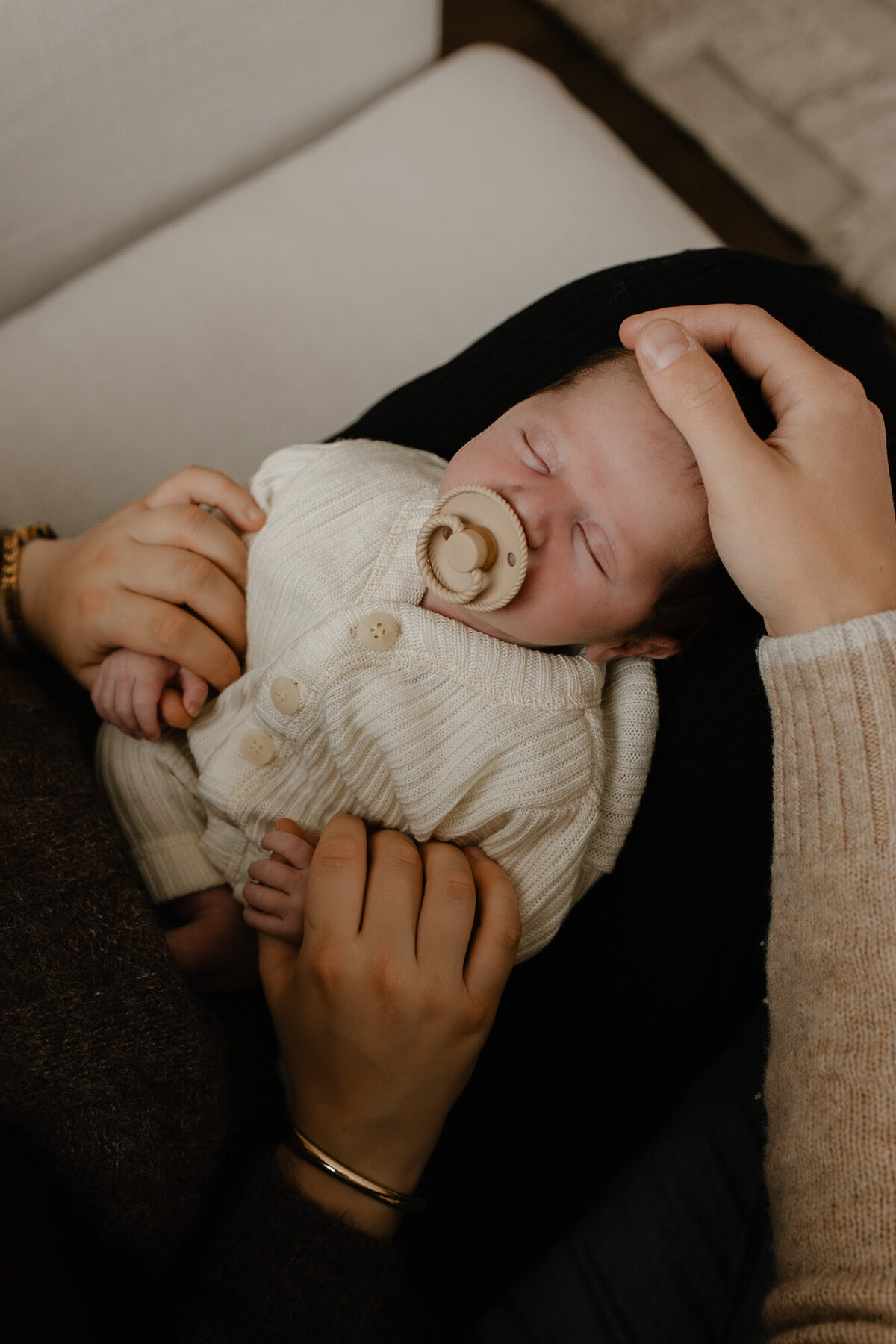 slapende newbon baby in de handen van zijn mama en papa tijdens een newborn fotoshoot te Bonheiden.