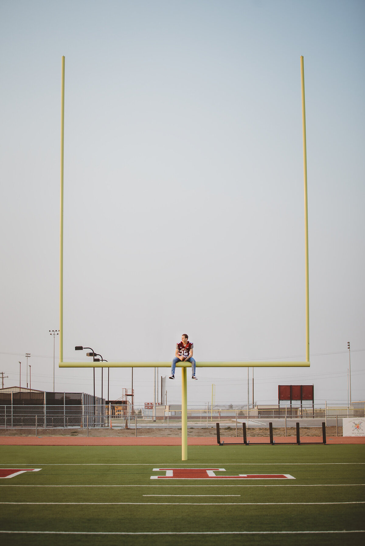 Senior boy sitting on top of goal posts
