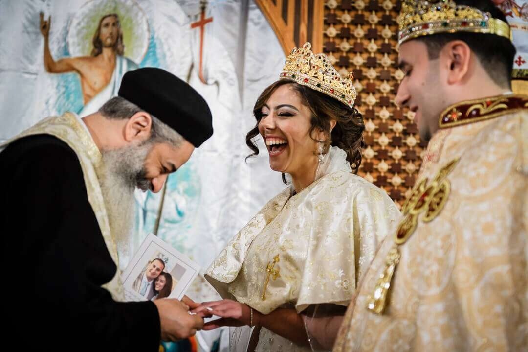 Bride laughing during Coptic Orthodox wedding ring ceremony at St. Mary’s Church in New Jersey