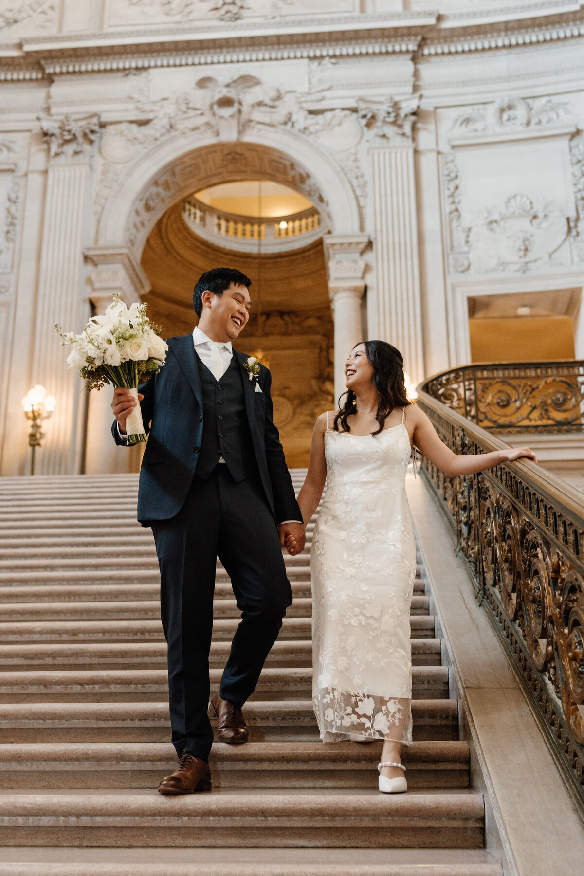 bride and groom walking down steps of san francisco city hall