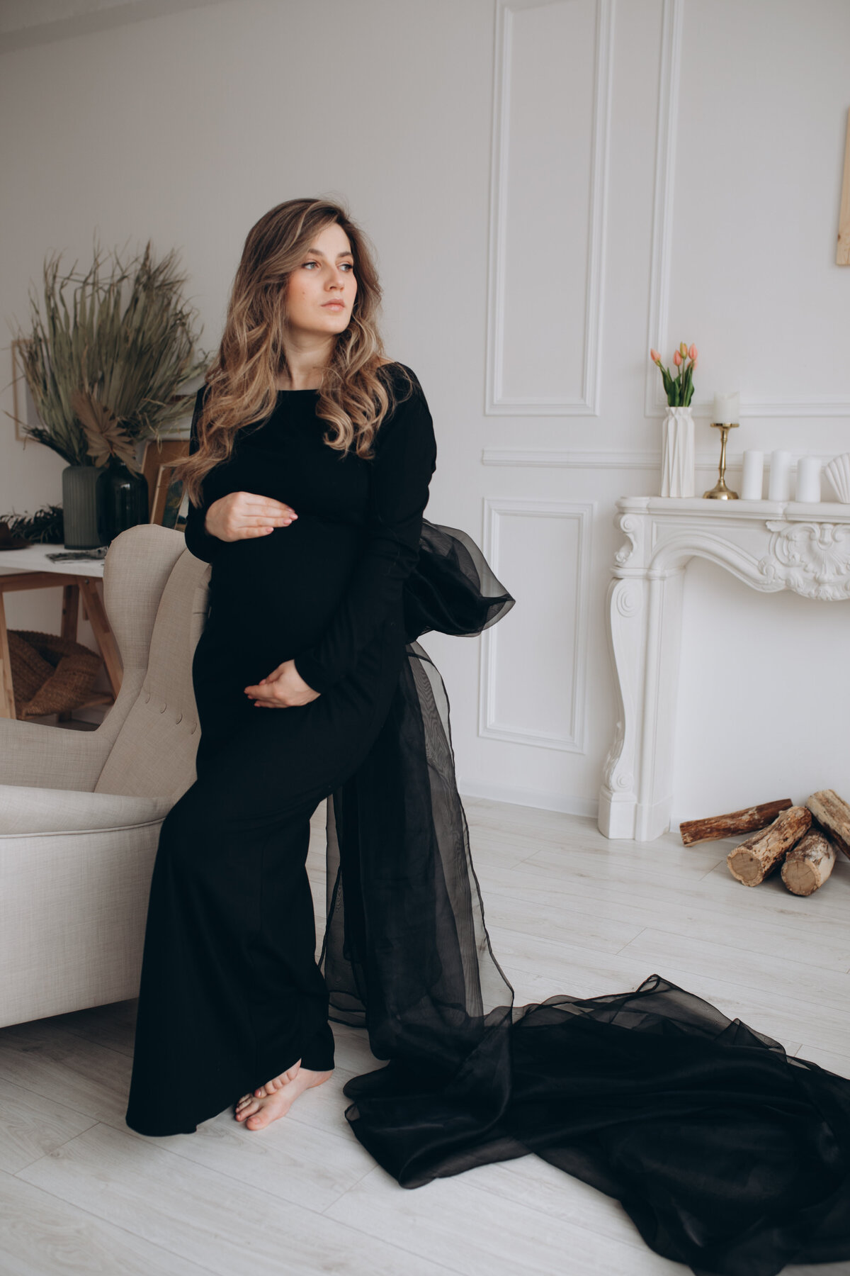 pregnant-woman-black-dress-sitting-chair-studio-with-white-background-pregnant-woman-touching-belly
