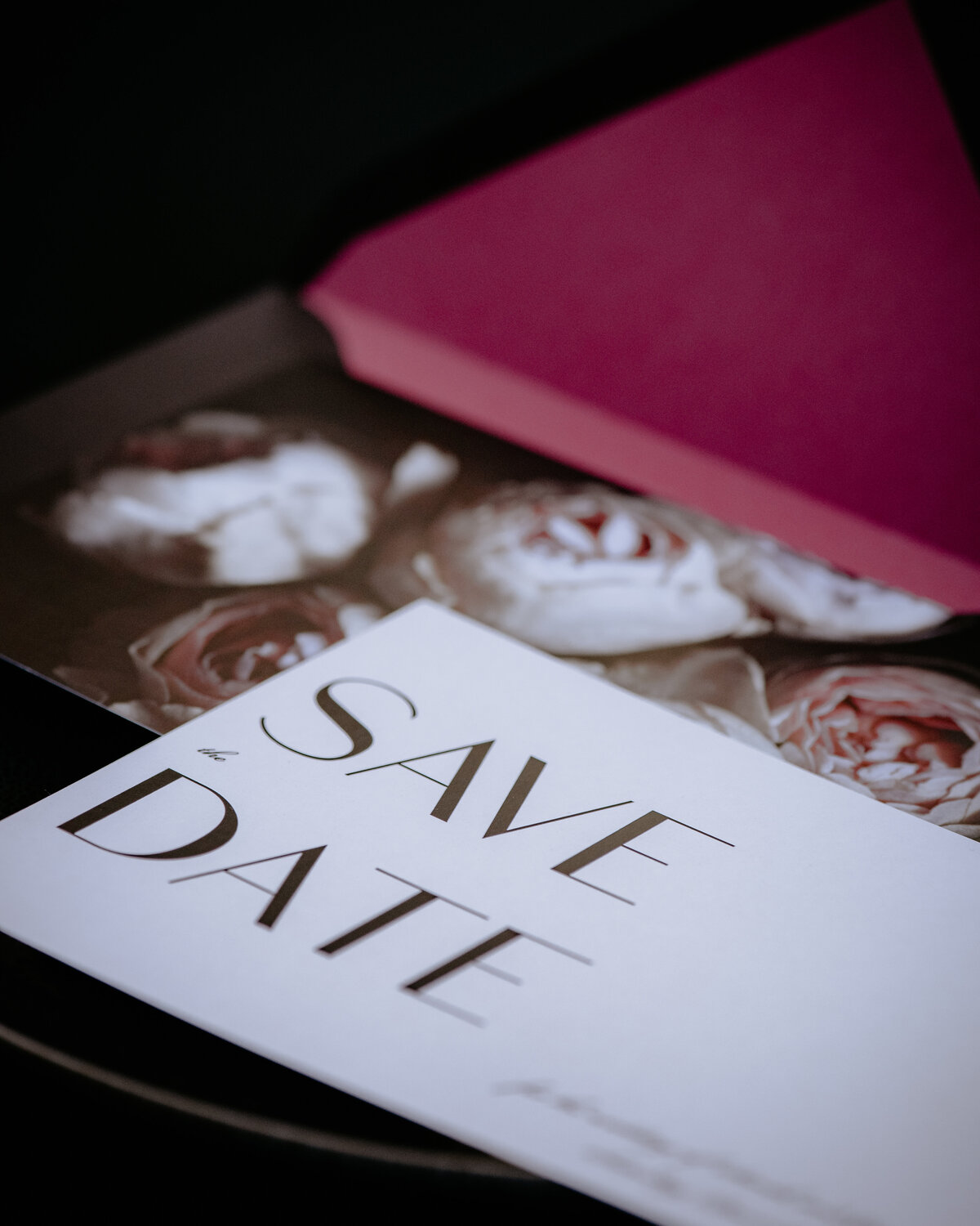 Dark save the date card with bold fonts and pink roses