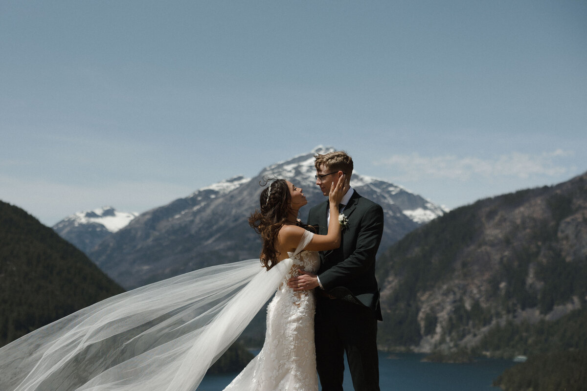 bride and groom standing on cliff with mountains in background