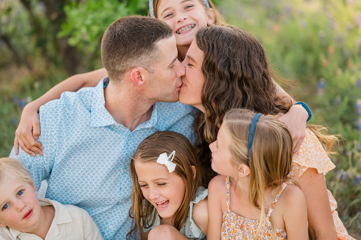San Antonio family photo of a mom and dad kissing surrounded by kids.