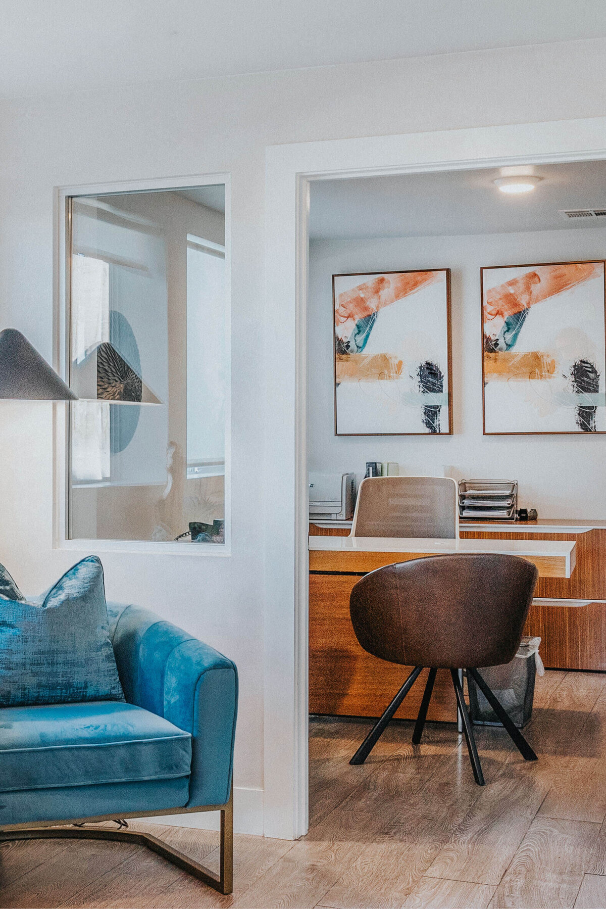 Cozy lounge at Sunterra in Oceanside featuring blue chairs, abstract art, and a modern office space.