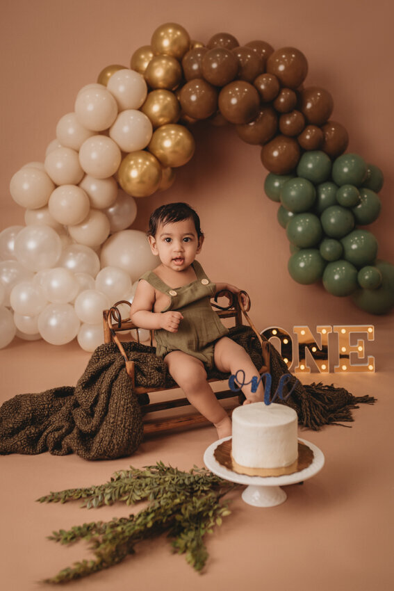 Cake smash milestone session with Atlanta, Georgia cake smash photographer. Milestone photography session with earthy tones, balloon garland and sweet baby boy eating cake for his first birthday.