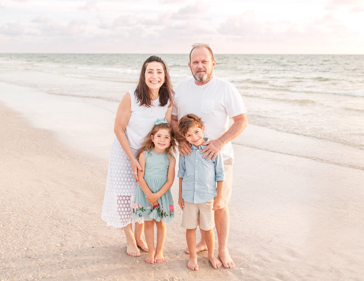 Children laughing and playing in the sand during a Clearwater Beach family session.