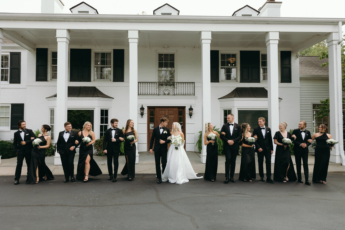 Bride and groom with their wedding party in front of a historic building, captured by Ryann B Photography in Indianapolis.