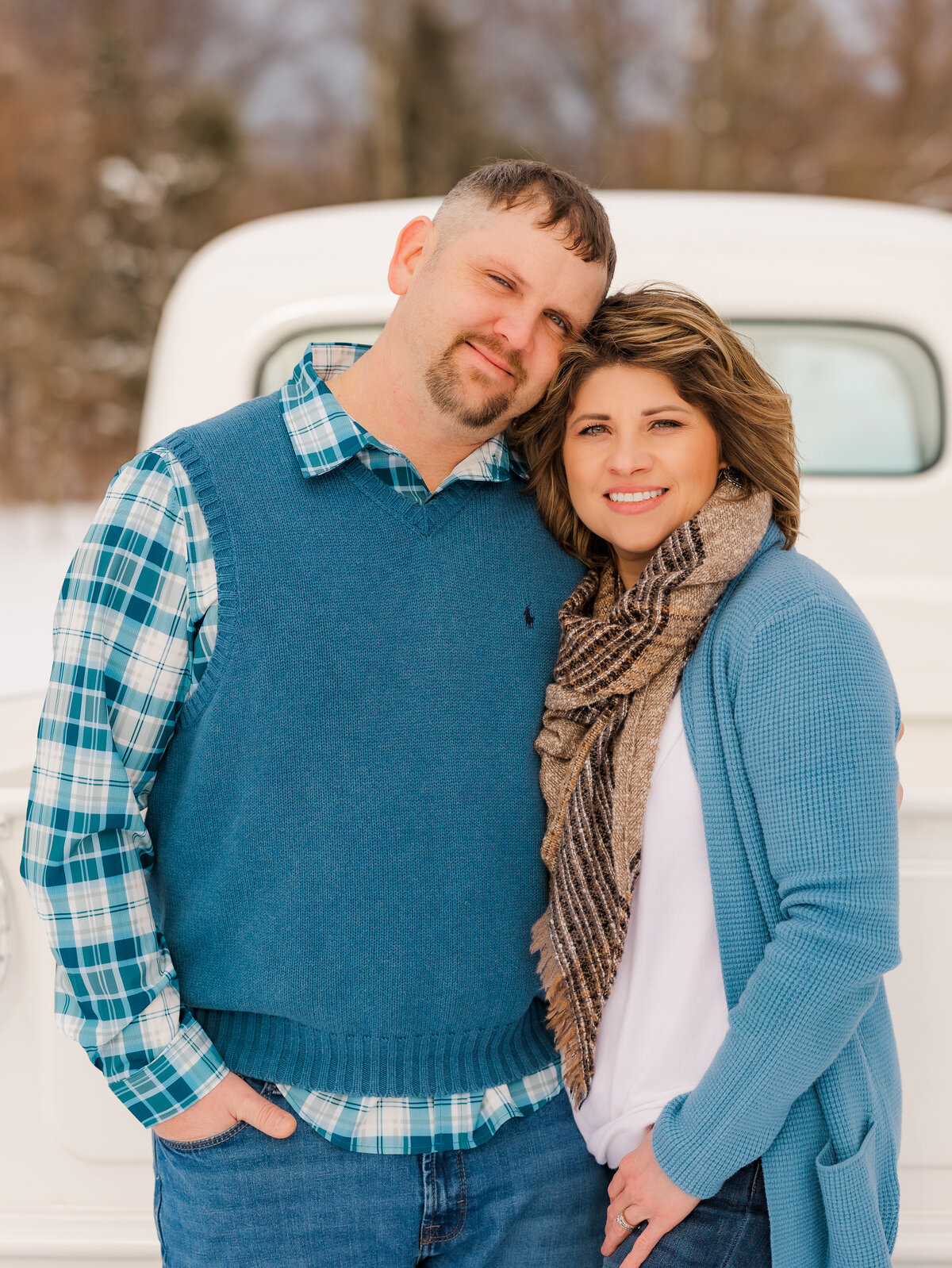 Husband and wife standing with their arms around each other by a white truck for Erie County couple’s photography.