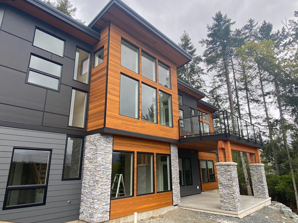 Modern home exterior with black, grey, cedar and stone pillars