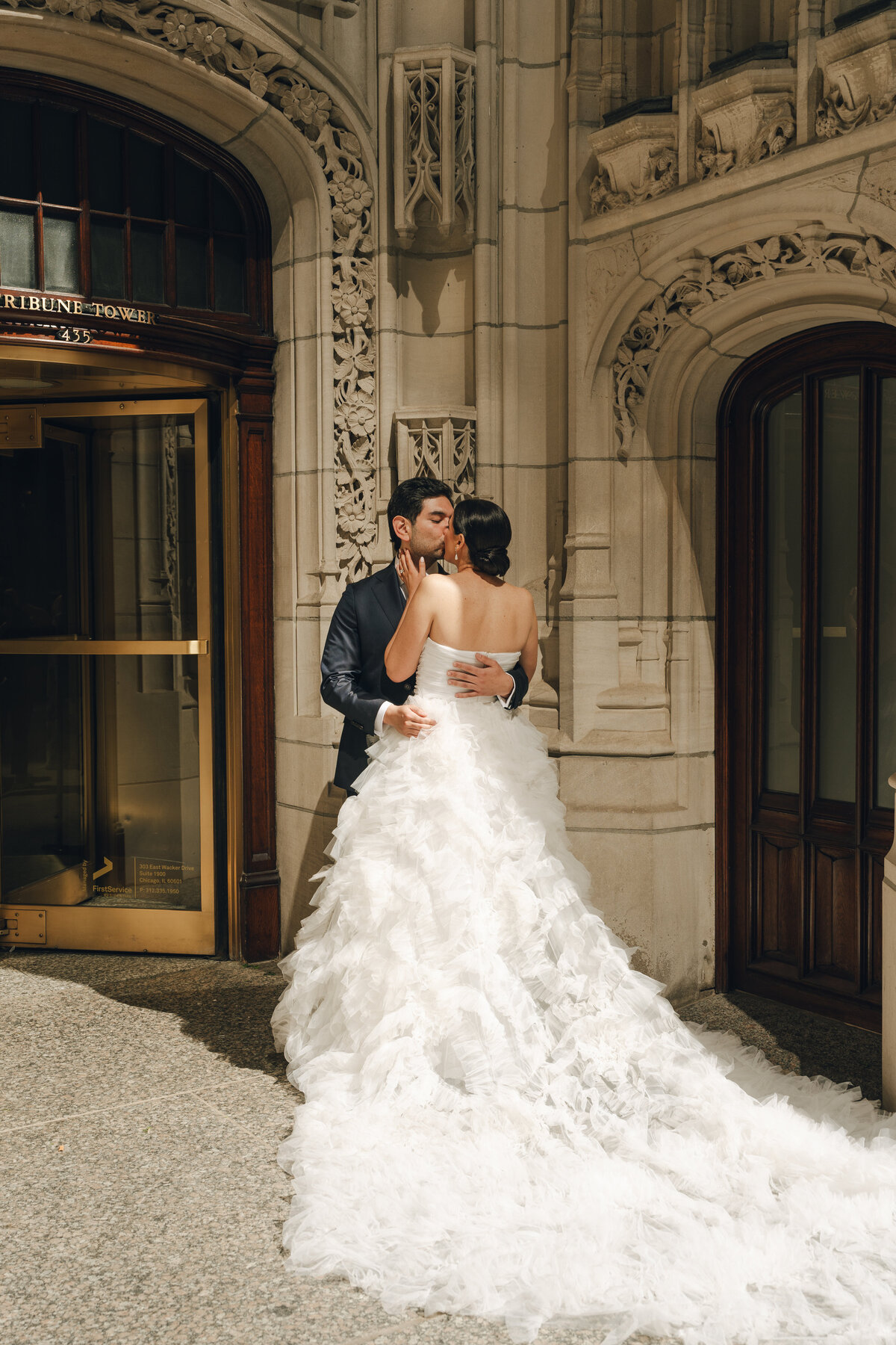 A bride and groom kissing outside of the Tribute Tower in Chicago Illinois on their wedding day. 
