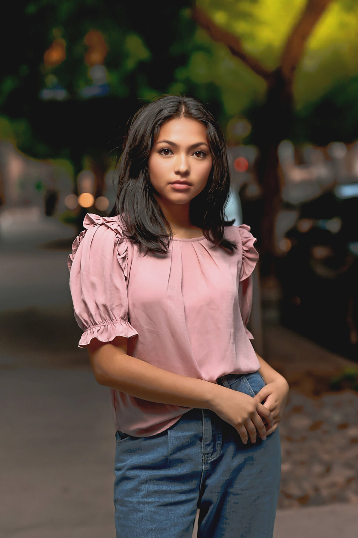 A woman walks on a street in downtown in a pink blouse at sunset