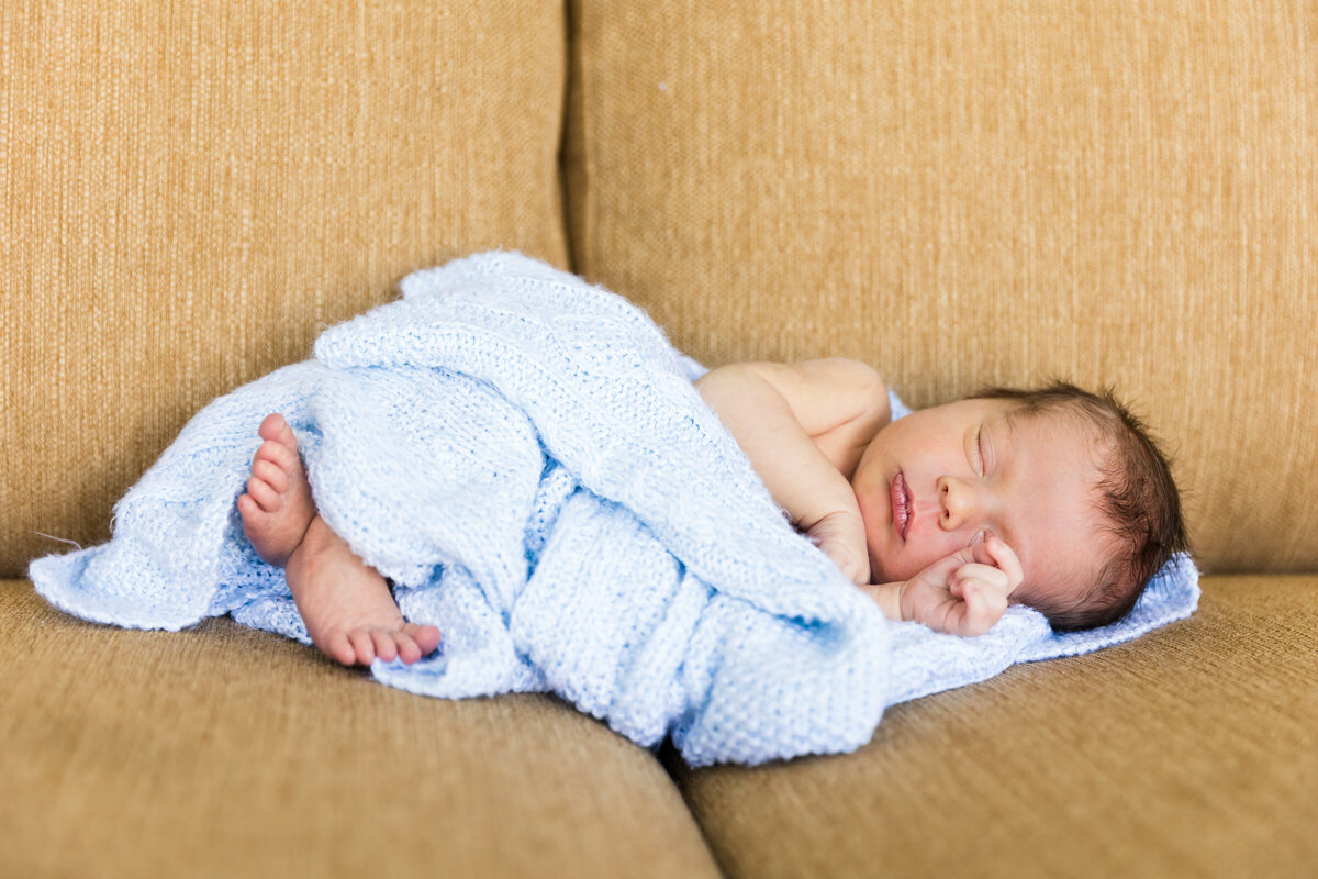 newborn baby sleeping on couch in lifestyle photography session