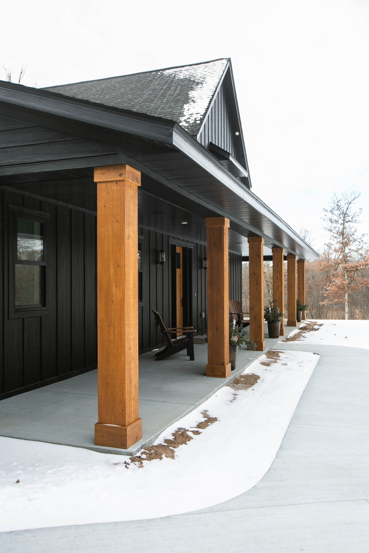 Exterior view of custom home in Elk River, Minnesota with black siding, wood details and front porch built by Cornerstone Custom Builds