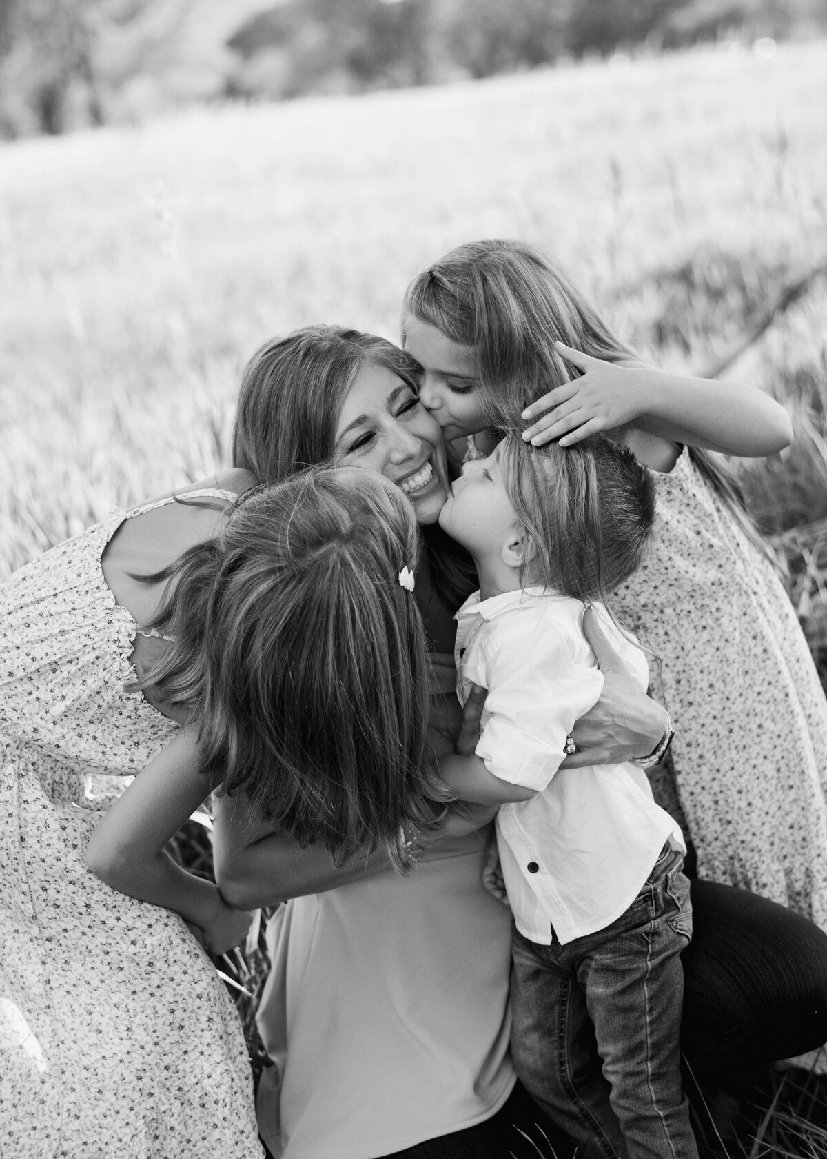 A mother is smothered with kisses from her three children