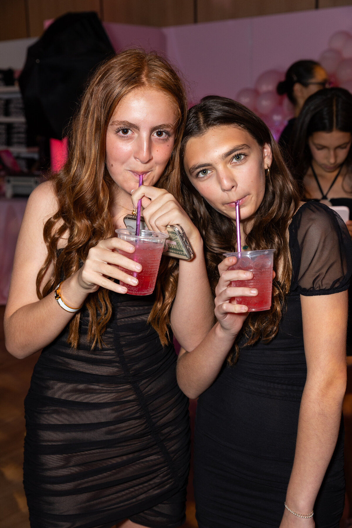 Two girls sipping on a drink