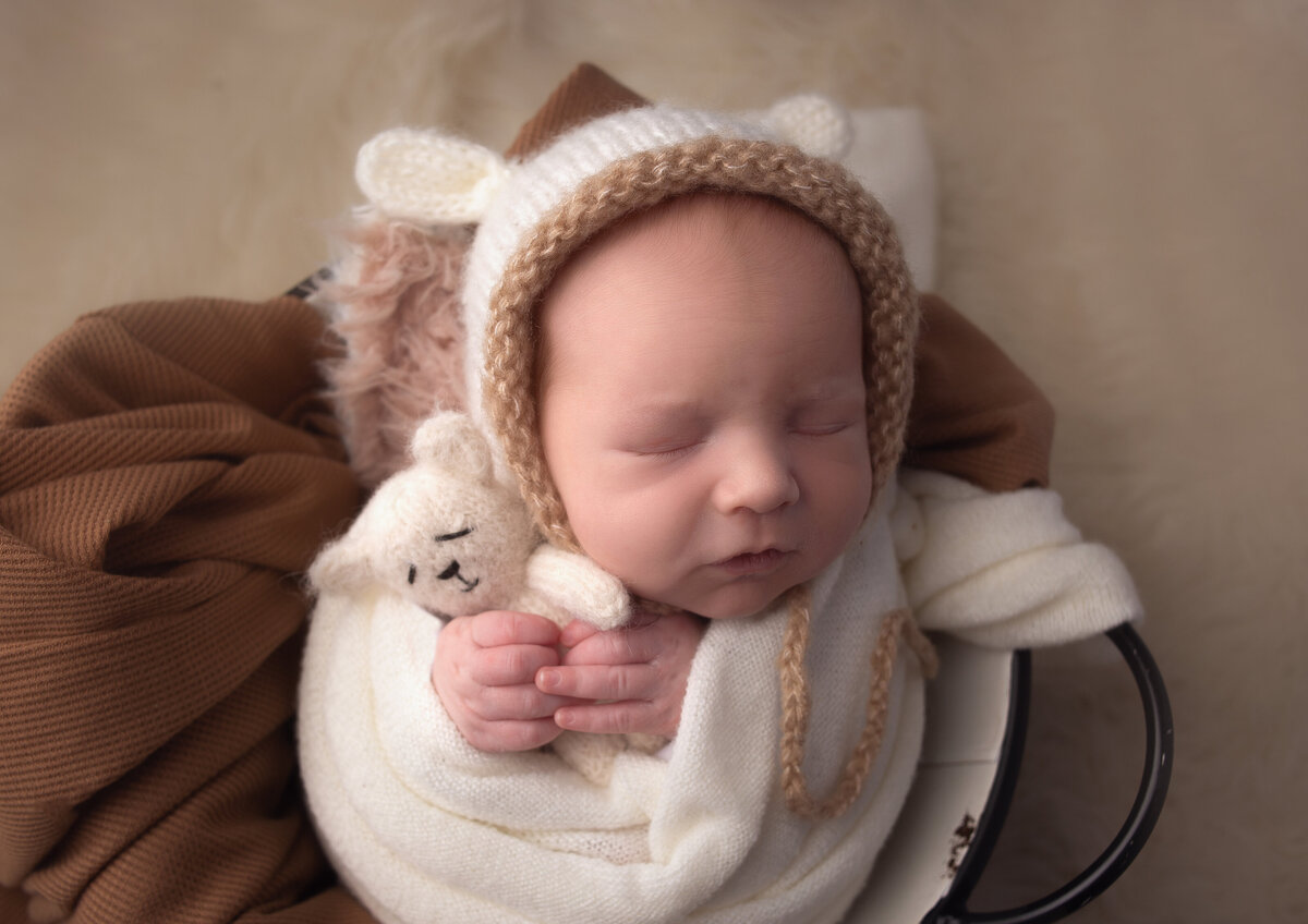 Baby wrapped in tan fabric holding teddy bear during newborn photoshoot with Nashville, TN newborn photographer