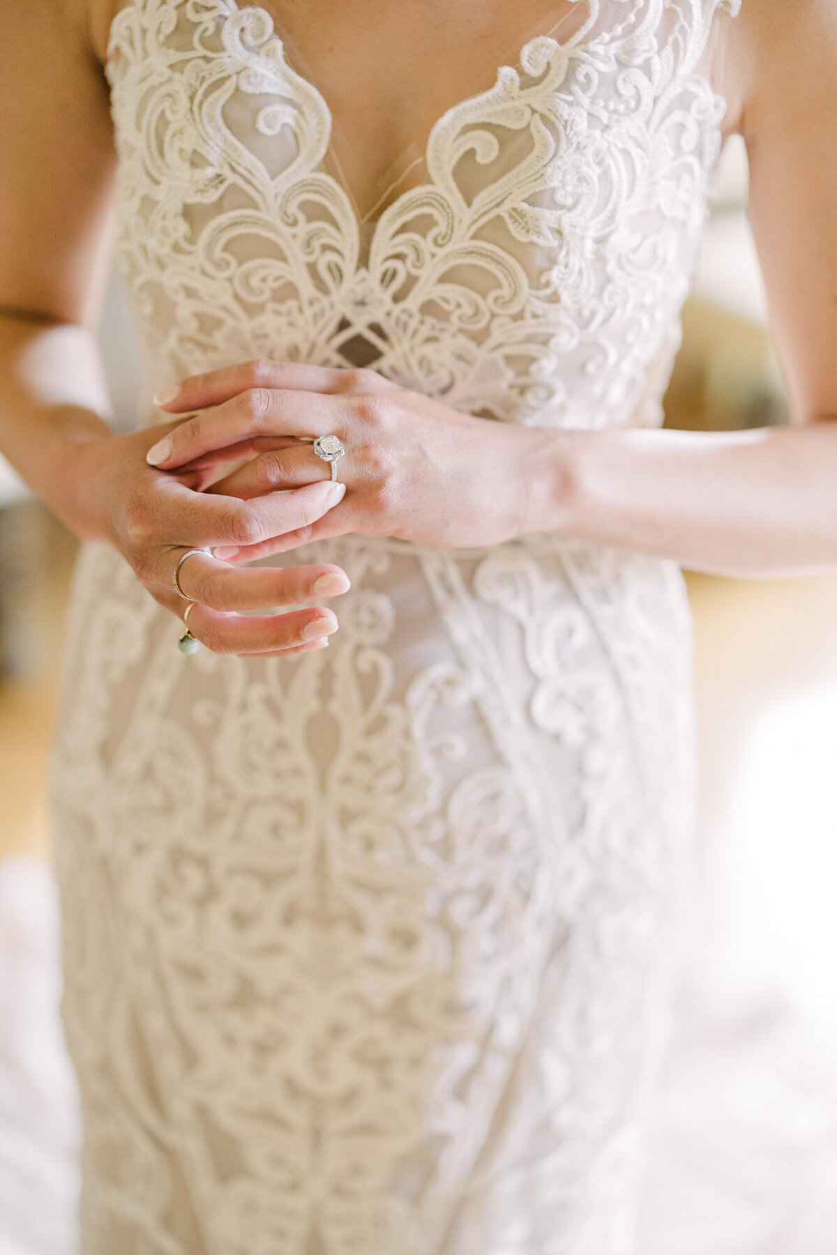 A delicate close-up wedding detail of a bride’s hands showcasing her sparkling engagement ring.