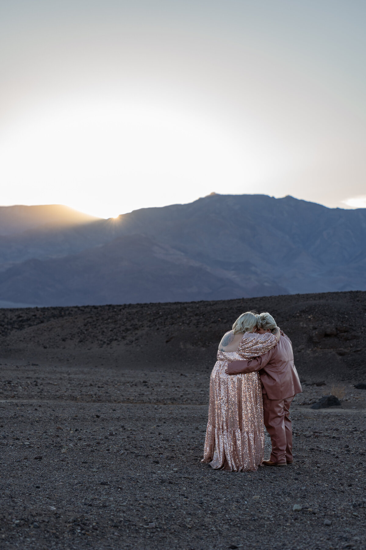 A couple with their arms around each other watching the sunset
