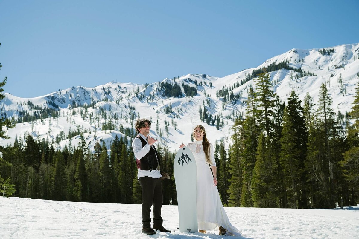 couple with snowskate during winter elopement with mountains in background