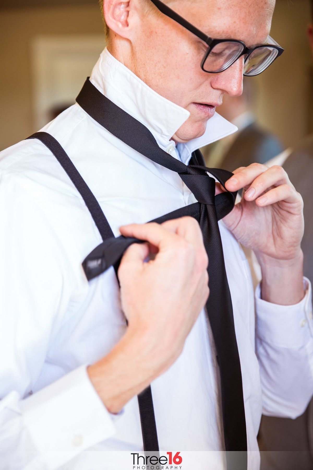 Groom tying his tie while getting dressed