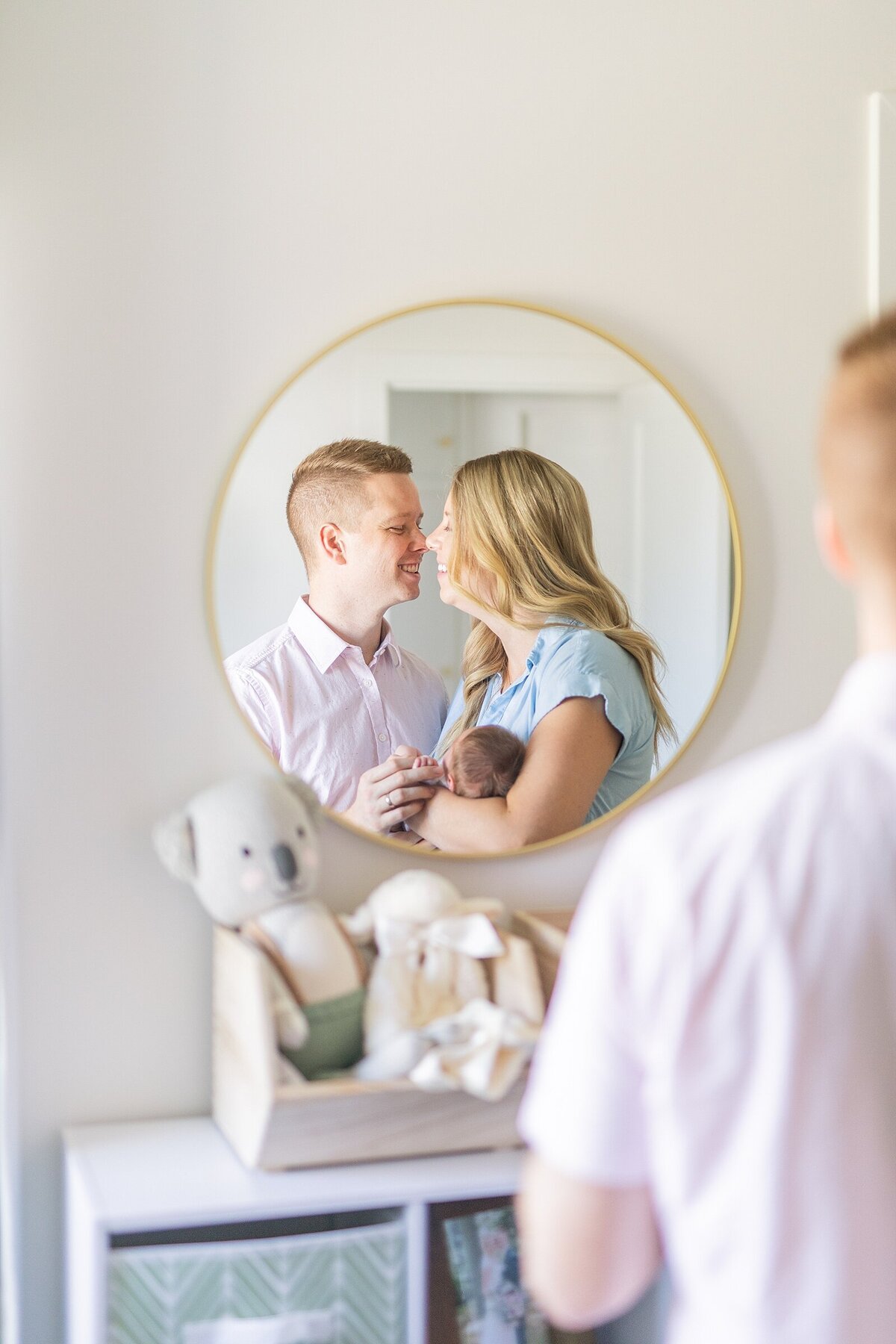 Mom and dad holding newborn baby in mirror reflection in San Diego.