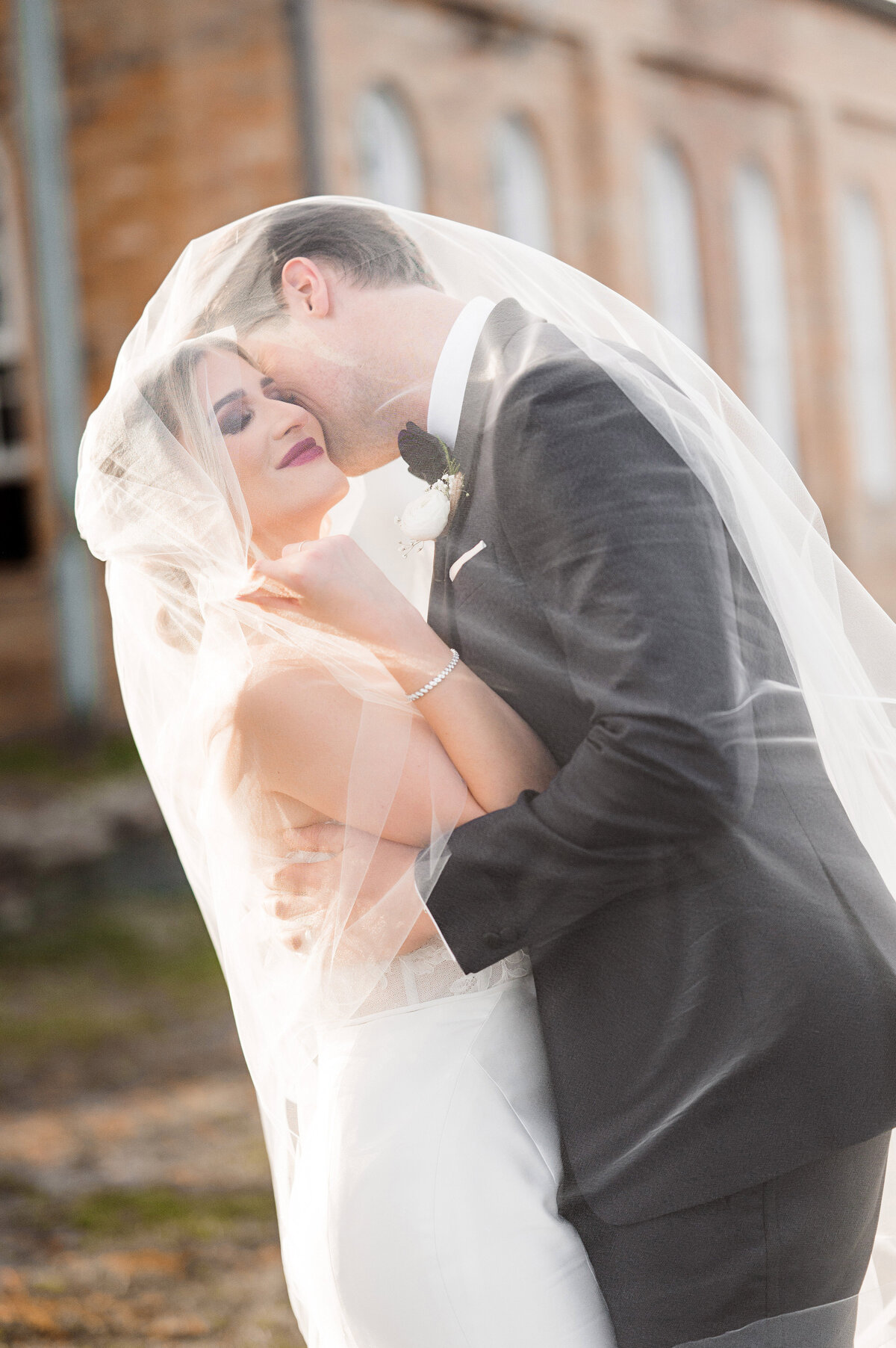 bride and groom under veil at pump house wedding