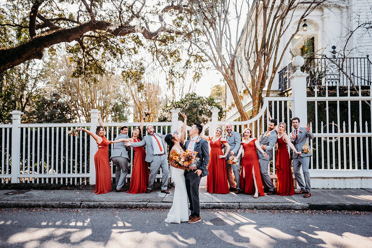 a bride, groom and their wedding party all rejoicing in a fun pose