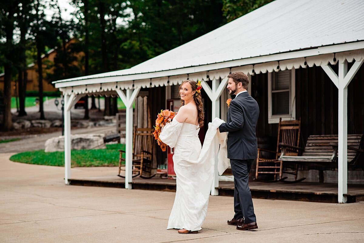 Bride walking away while groom hold the train of her dress