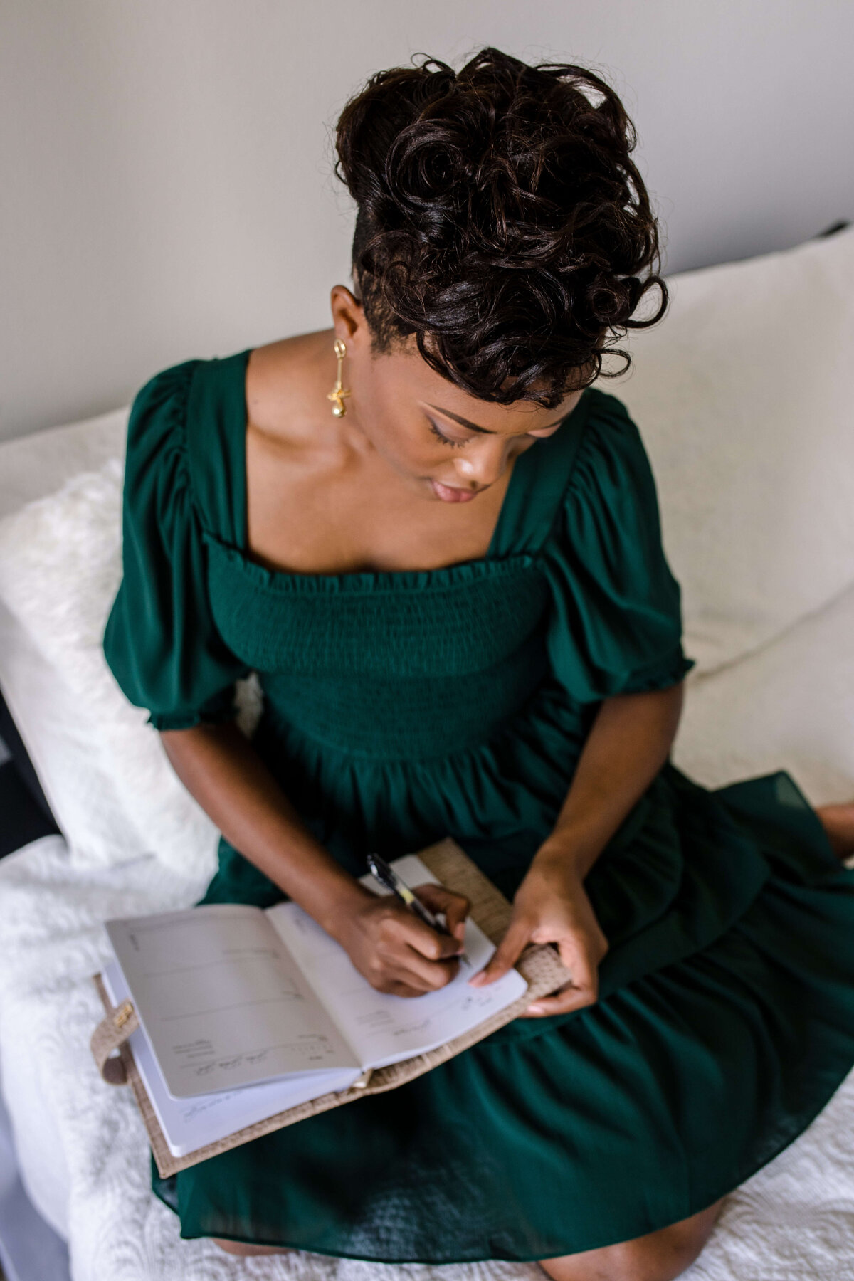 Orlando photographer photographs woman writing in a journal while sitting on a white bed  for a detail shot for her brand photography