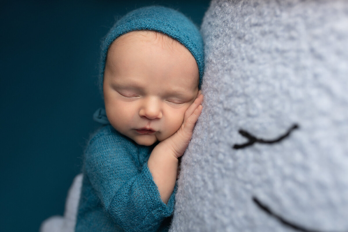 Close-up of a sleeping newborn’s face snuggled into a smiling plush whale – Southlake baby photographer.
