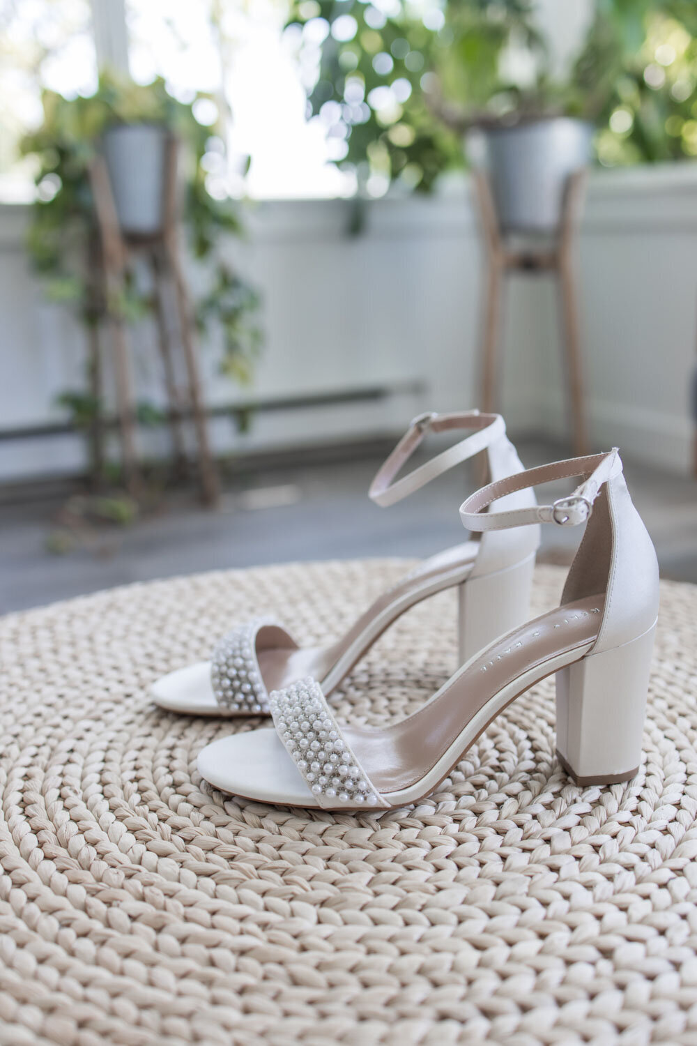 White bridal heels with pearl details on woven round rug