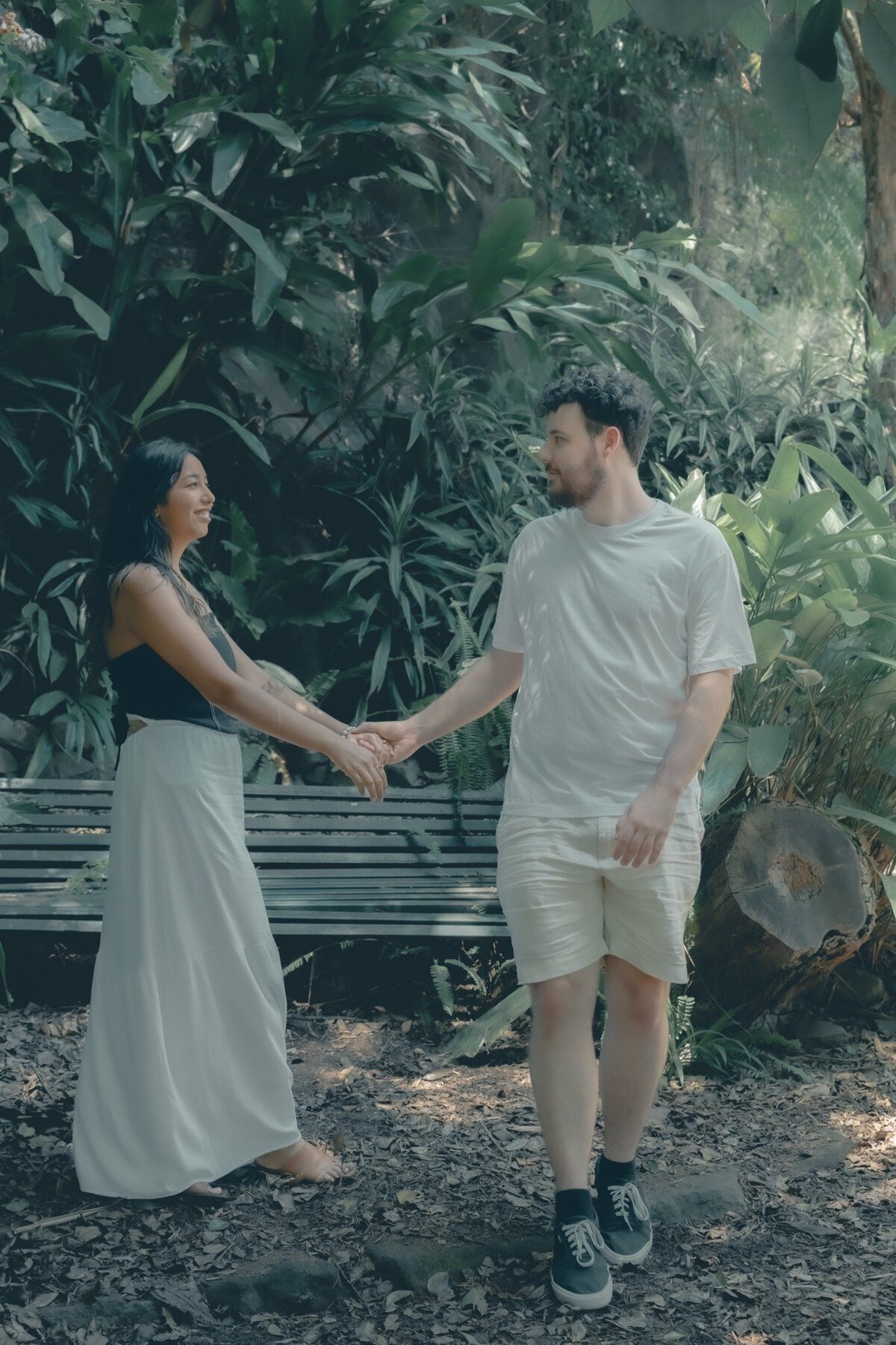 Natural engagement portrait of a couple smiling and holding hands in the greenery of Wendy’s Secret Garden, Sydney.