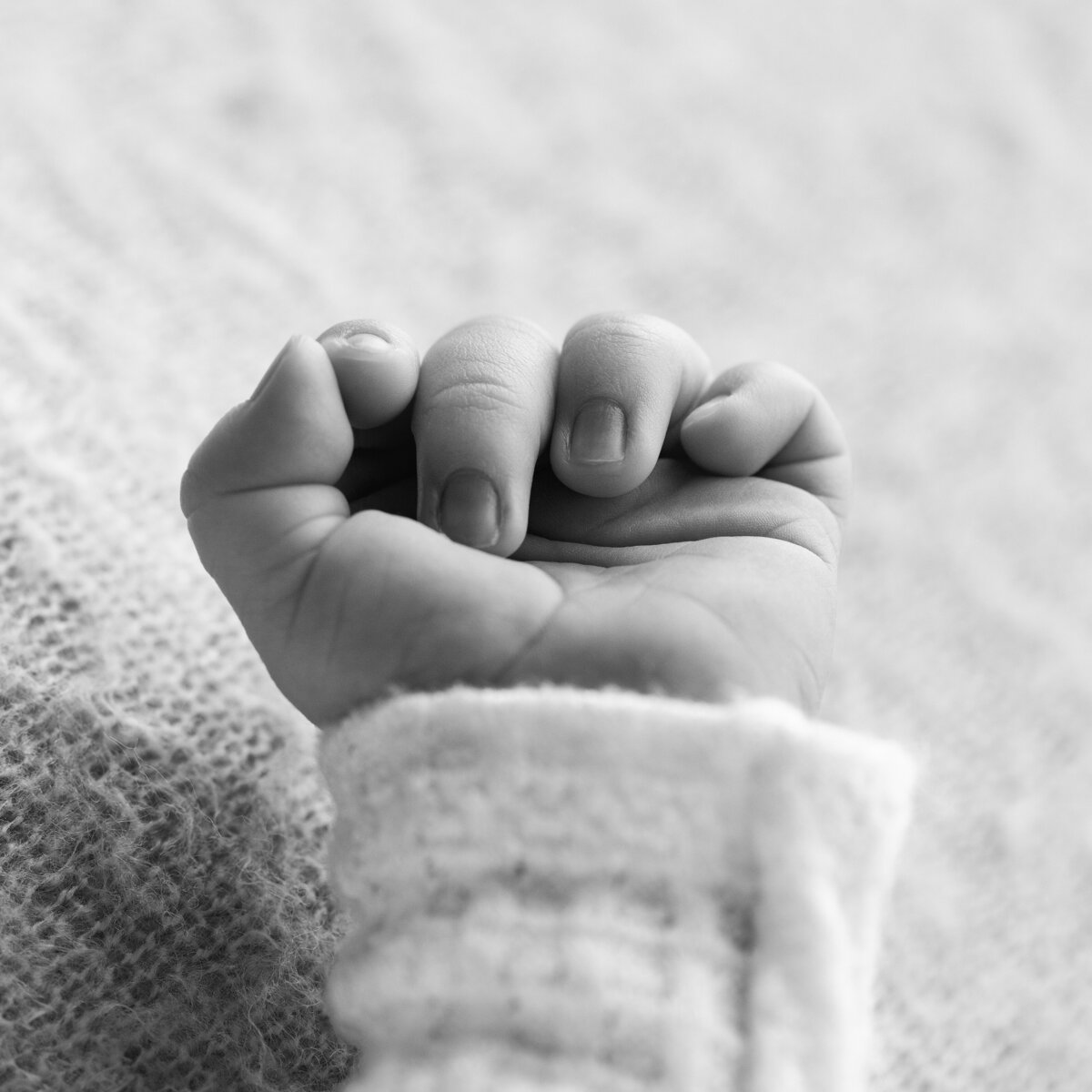 A tender macro image of a newborn’s hand curled into a tiny fist—symbolizing new strength and first expressions.
