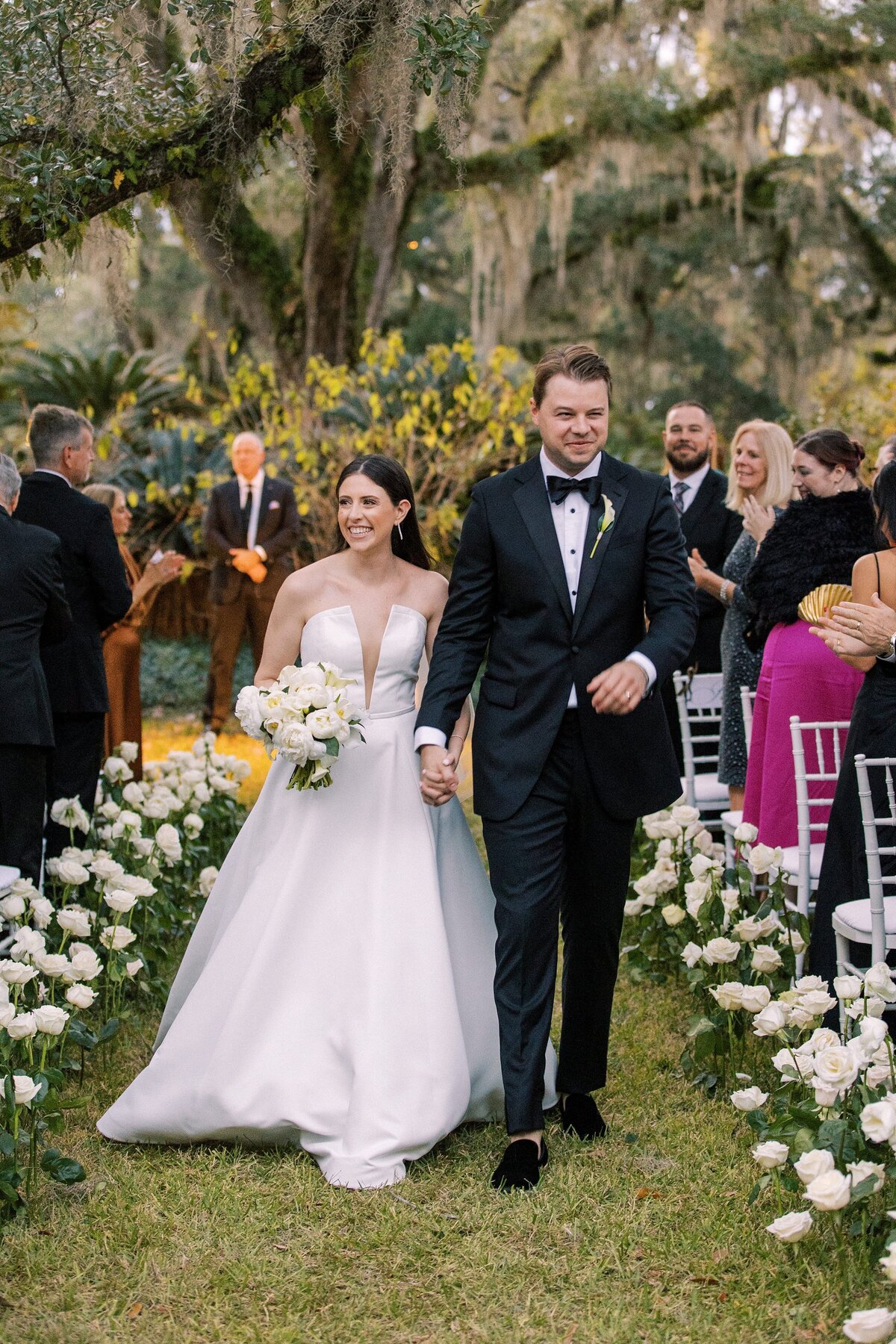 Bride and groom smile as they walk arm in arm back down the aisle after their wedding ceremony