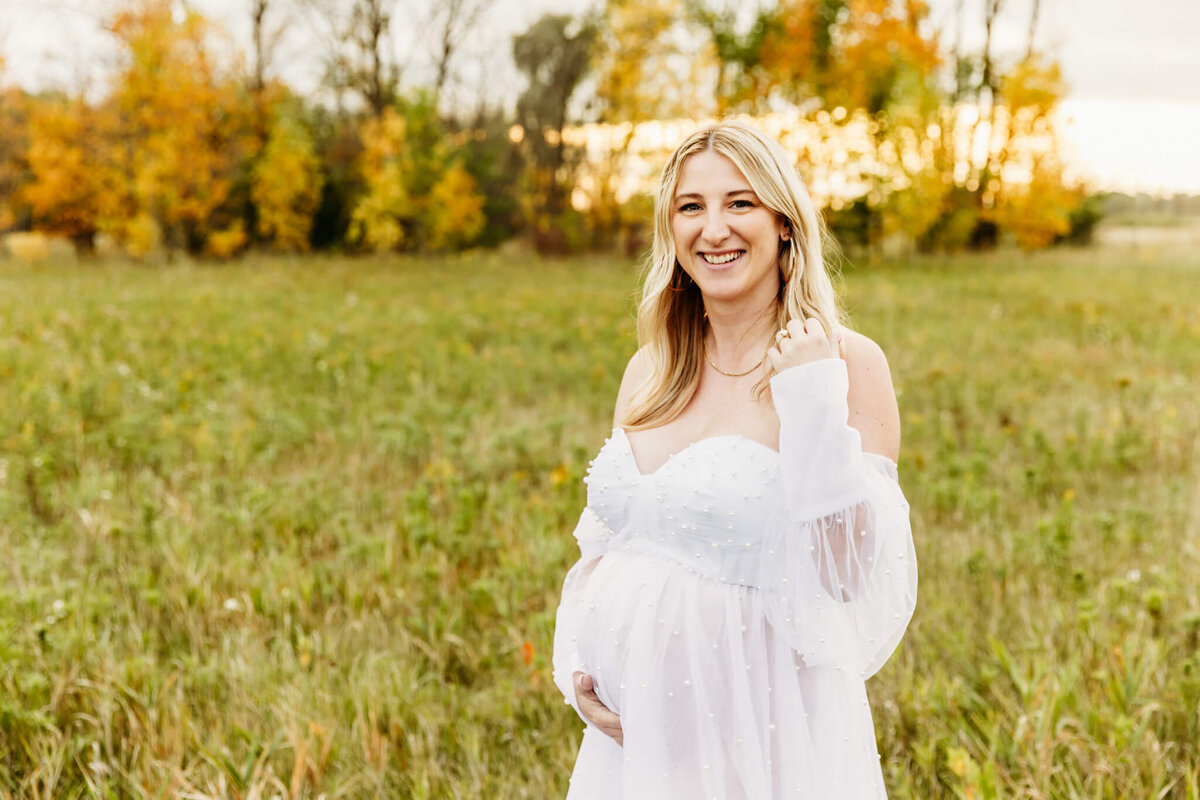 woman holding her baby bump and smiling during her Green Bay maternity photo session