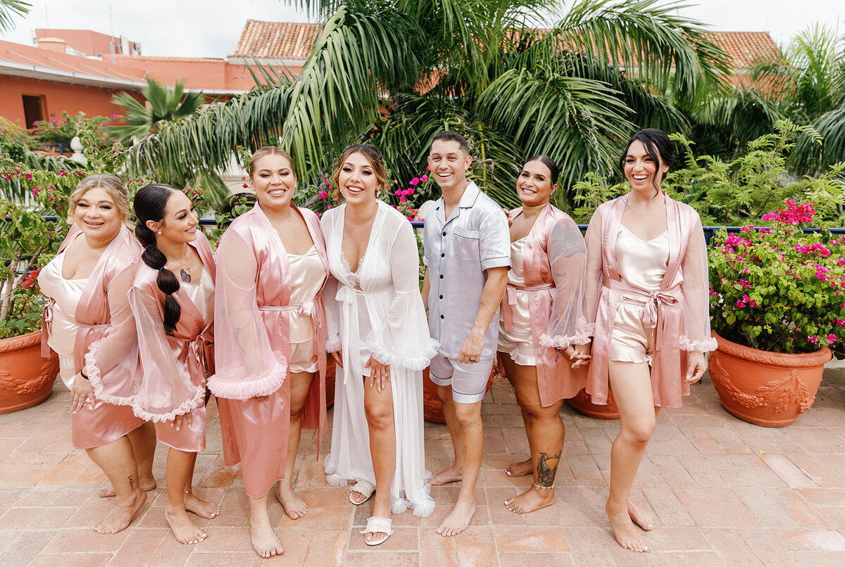 Victoria and her bridesmaids in blush satin robes, celebrating together before her Cartagena destination wedding ceremony.