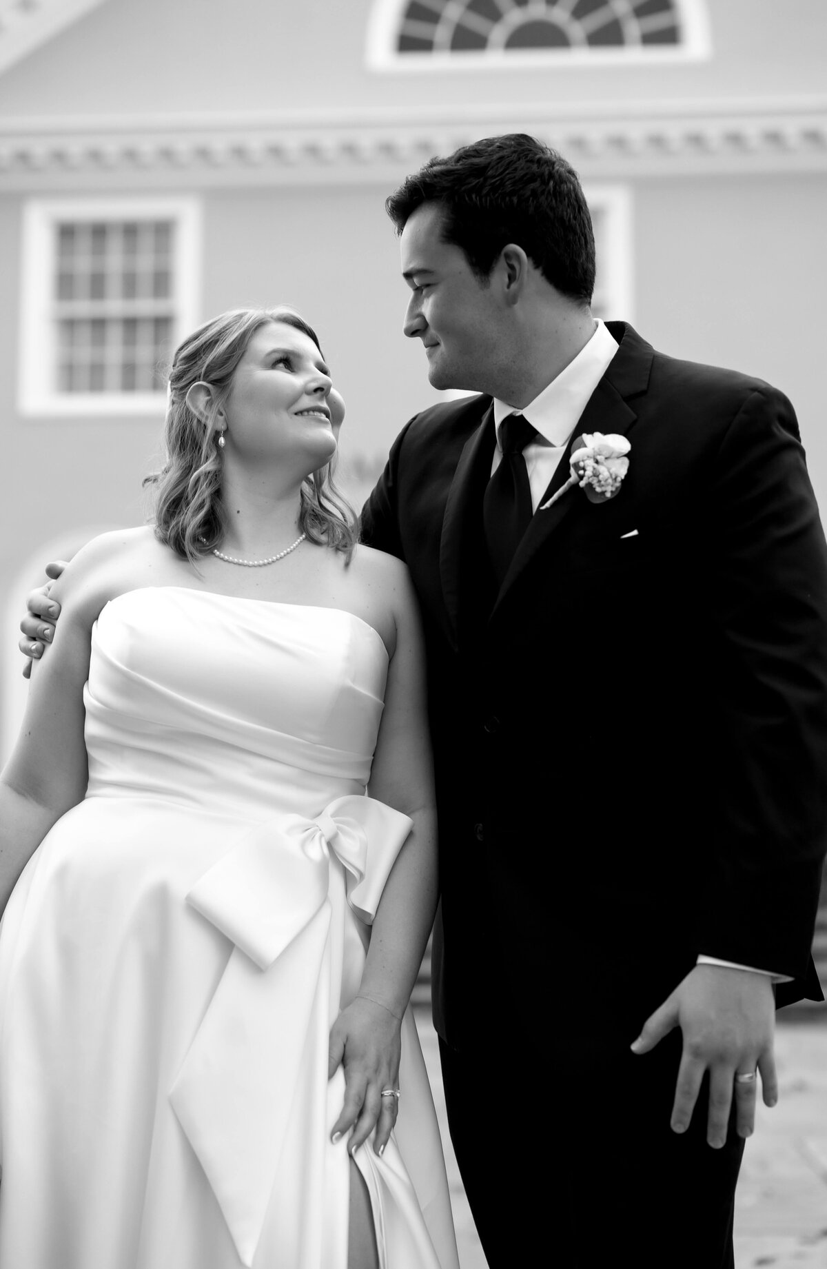 black and white wedding photo with bride adn groom smiling at one another with the grooms arm around the brides shoulder