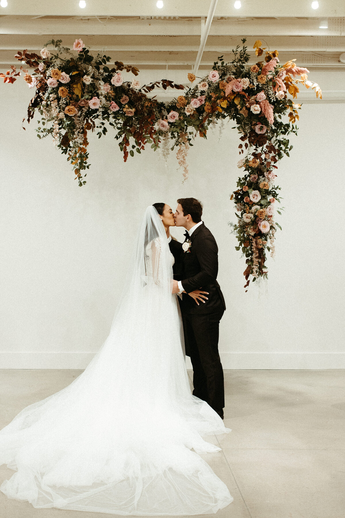 An eye-catching whimsical installation full of petal heavy roses and copper beech was the highlight of this art deco wedding. Terra cotta, burgundy, dusty pink, and other neutral florals warm up this ceremony. Designed by Rosemary and Finch in Nashville, TN.